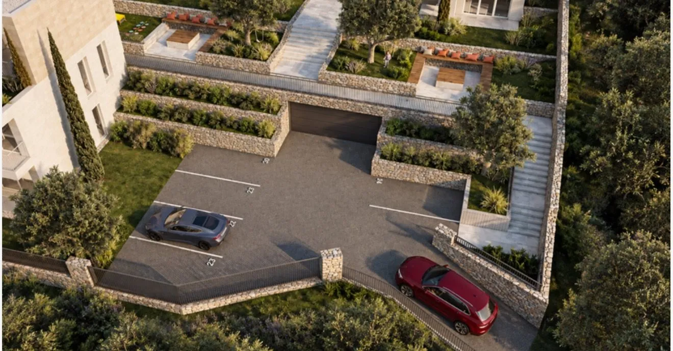 Pogled iz ptičje perspektive na dvorište sa parking prostorom i uređenim terasama.