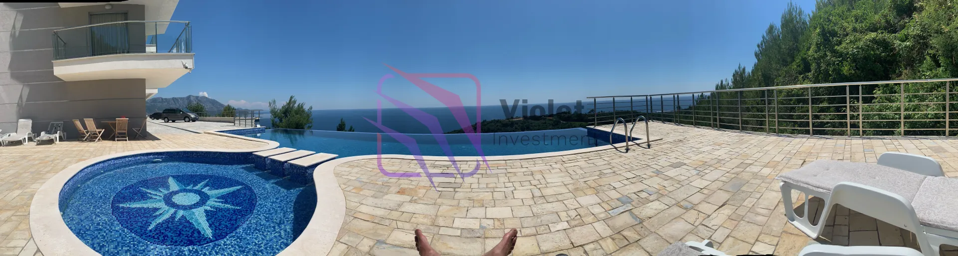Veliki bazen sa popločanom terasom i pogledom na more.
