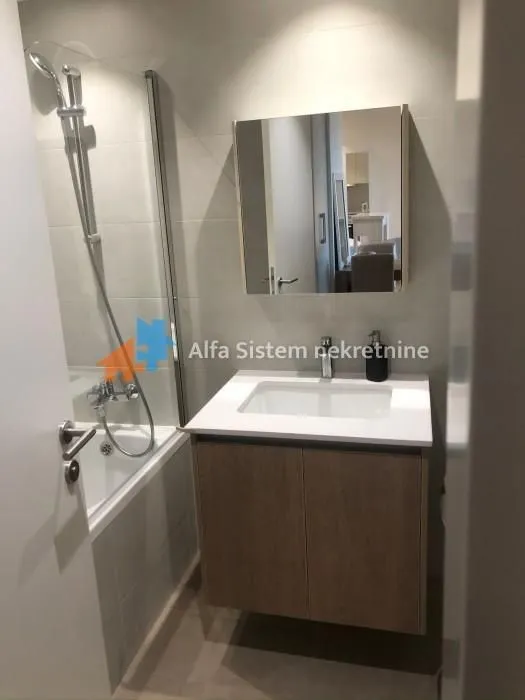 Modern bathroom with a sink, mirror, and bathtub.