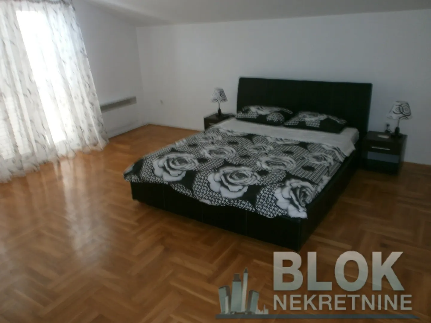 Bedroom with a large bed, parquet flooring, and nightstands.
