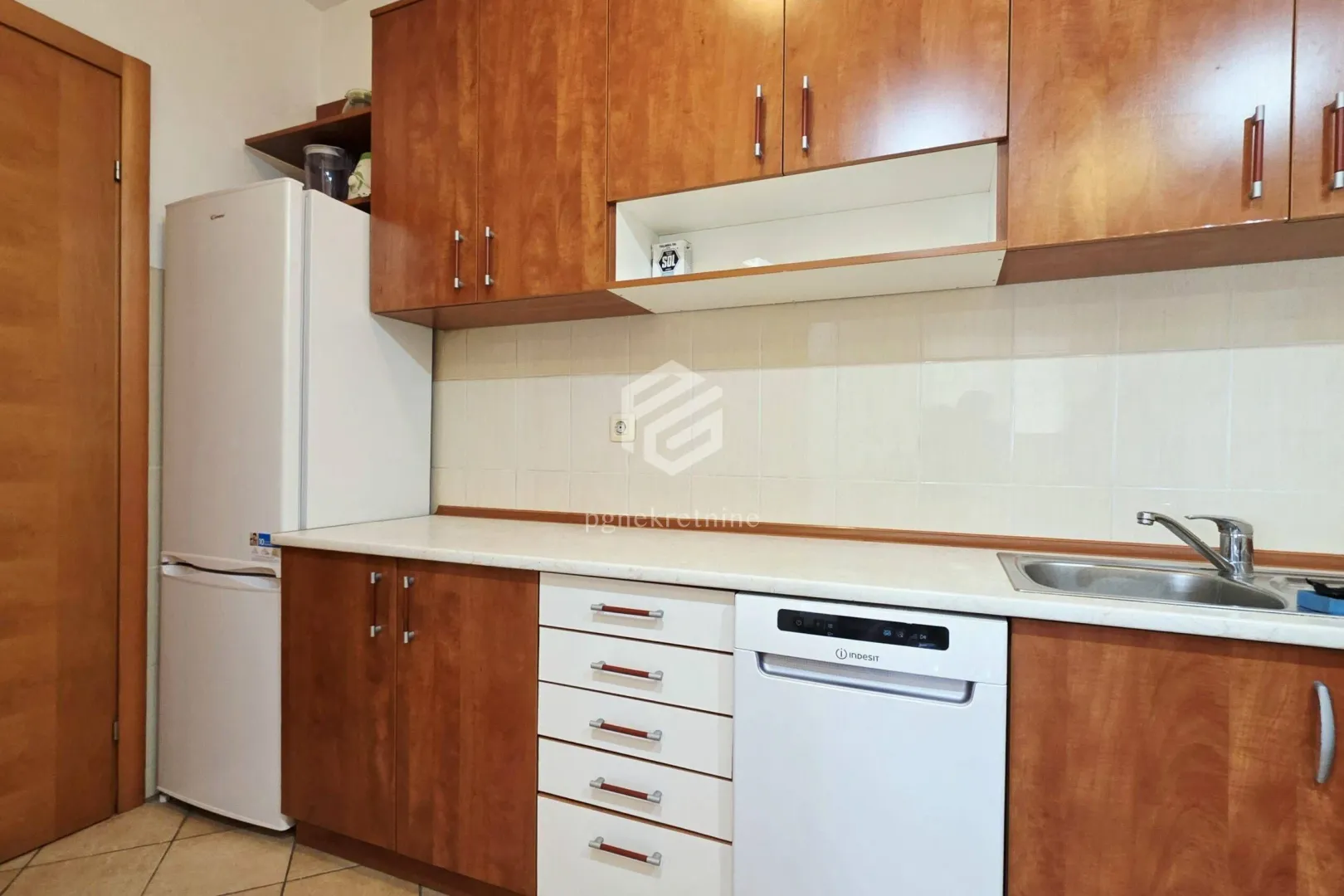 Kitchen with wooden cabinetry, refrigerator, sink, and built-in home appliances.