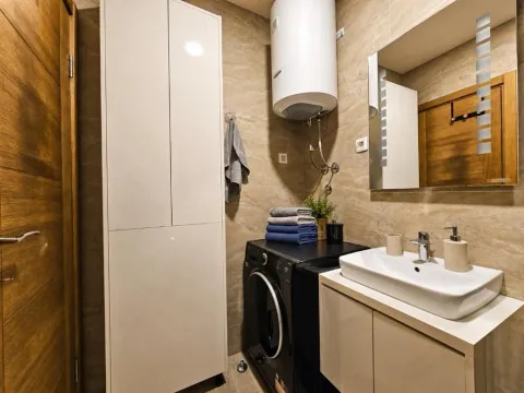 Bathroom equipped with a washbasin, cabinet, washing machine, and water heater. - image 3