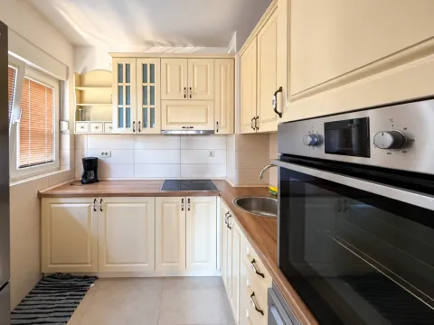Kitchen equipped with light wooden units and a built-in oven. - image 4