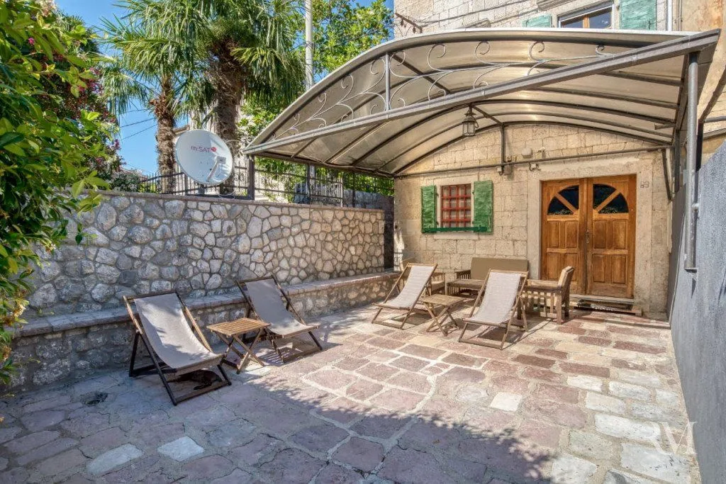 Paved courtyard with a canopy and sun loungers in front of the house.
