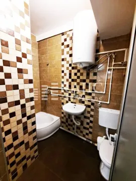 Smaller bathroom with ceramic tiles, shower cabin, sink, and water heater. - image 9
