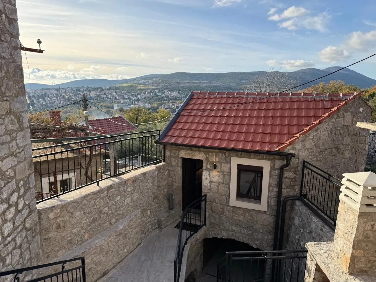 Kamena kuća sa popločanim dvorištem i pogledom na okolna brda.