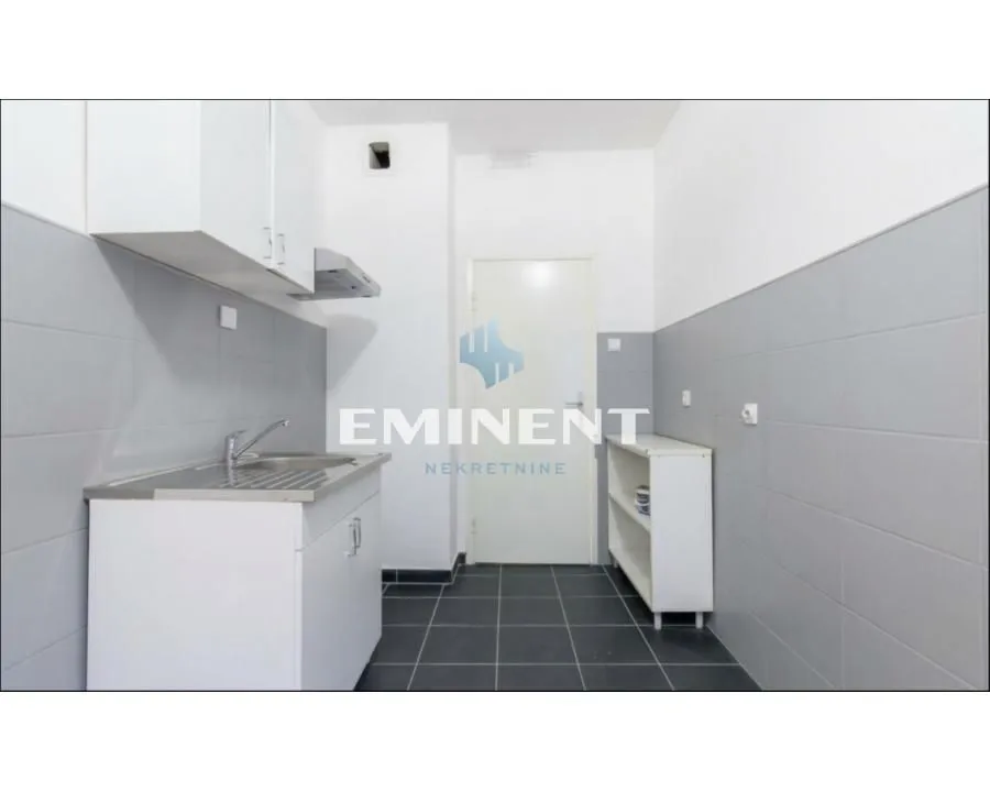 Smaller kitchen with a sink, cabinetry, and grey-and-white tiles.