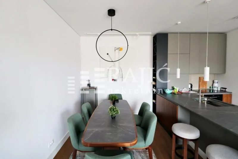 Modern dining area with a table and green chairs connected to the kitchen.