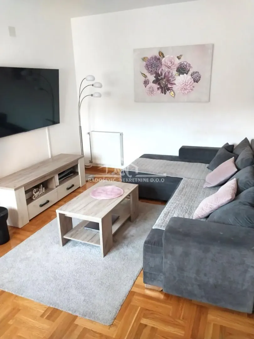 Living room with a corner sofa, television, and wooden coffee table.