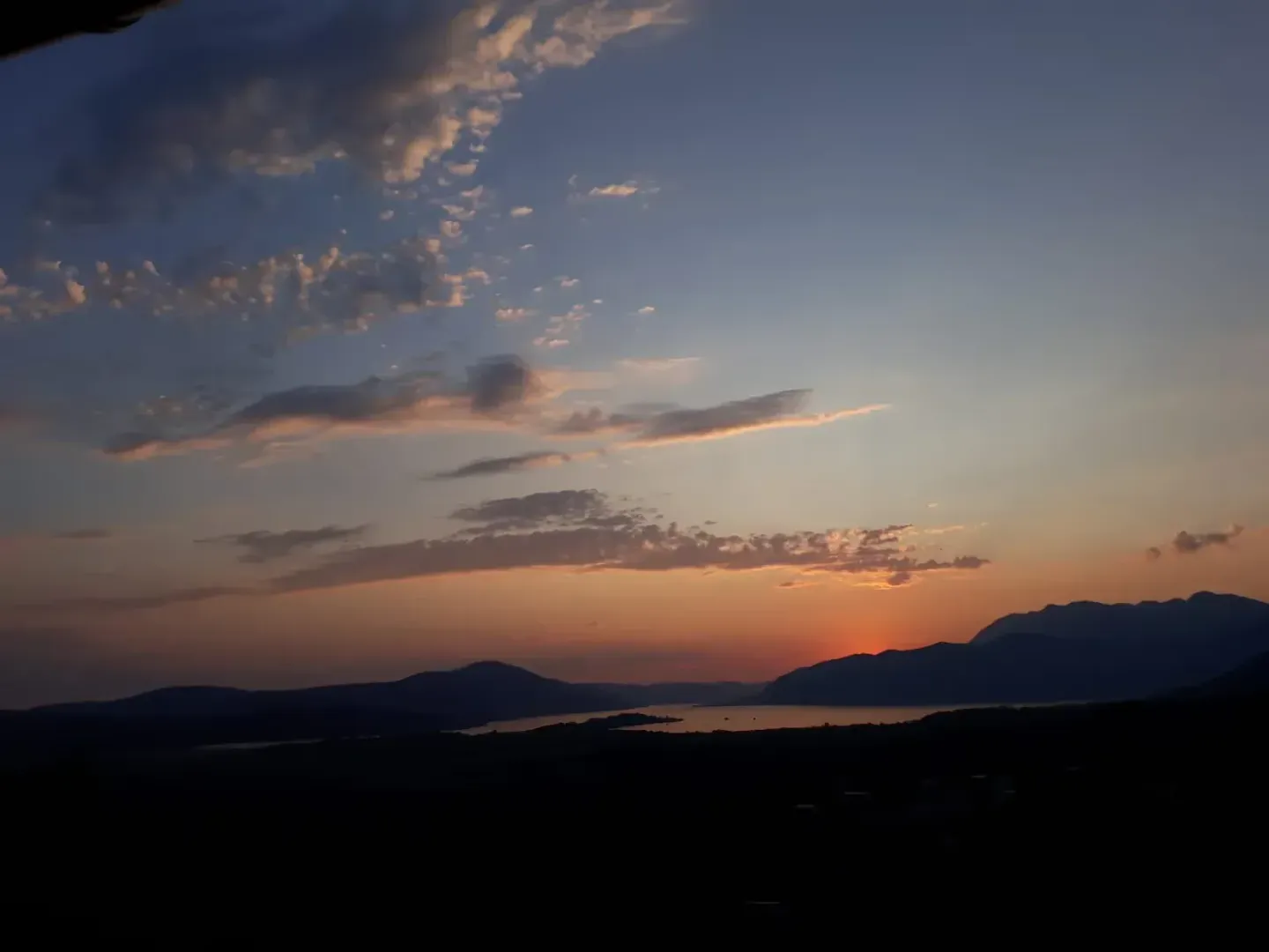 View of the sunset over mountains and water.