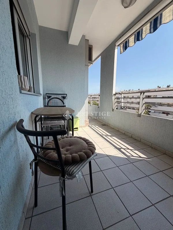 A long balcony with a table and chairs.