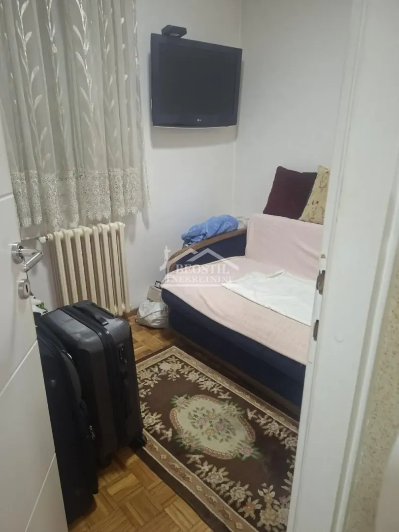 Smaller room with a sofa, rug, and wall-mounted TV.