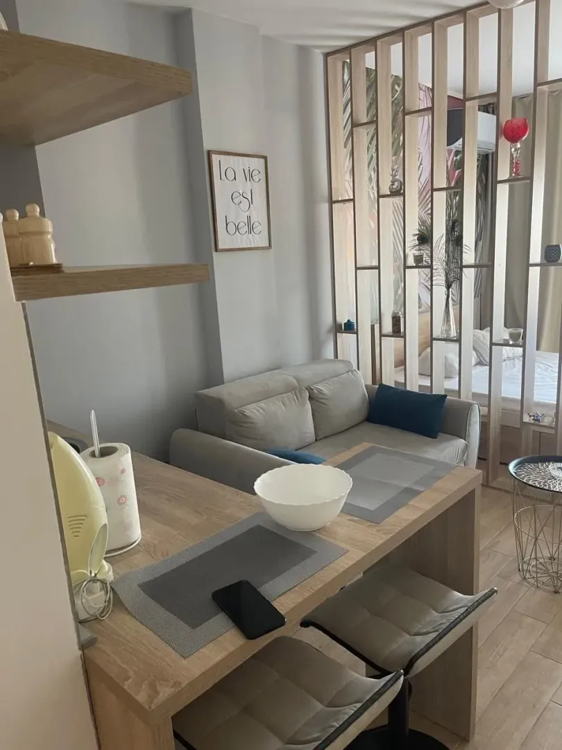 Living room with a sofa, dining table, and wooden partition panel.