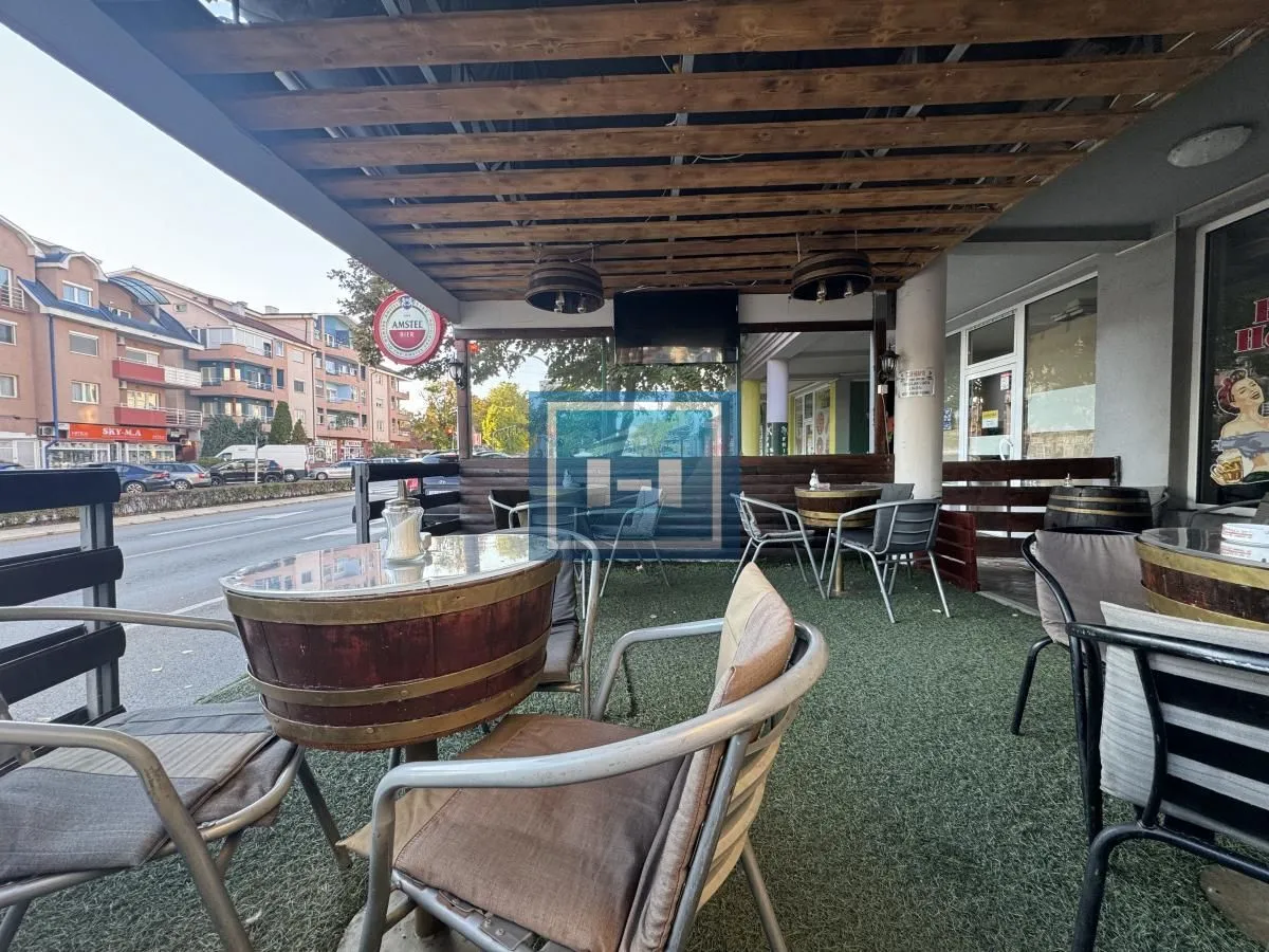 Covered terrace of a catering establishment with tables and chairs by the street.