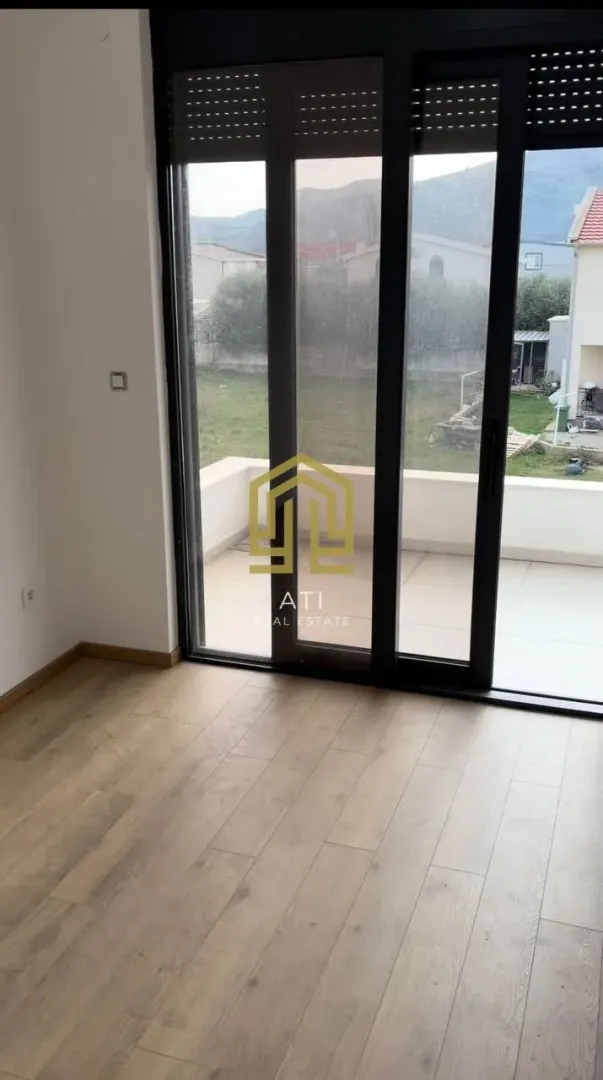 Prazna soba sa drvenim podom i izlazom na terasu.