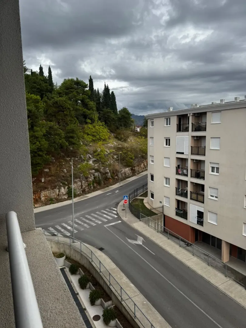 View from the terrace overlooking the street, adjacent building, and greenery.
