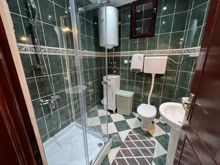 A bathroom featuring a shower cabin and green tiling.