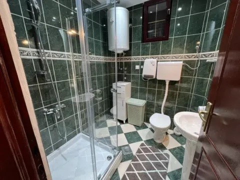 A bathroom featuring a shower cabin and green tiling. - image 19