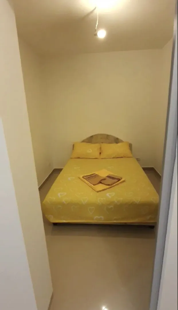 Spavaća soba sa bračnim krevetom i žutom posteljinom.