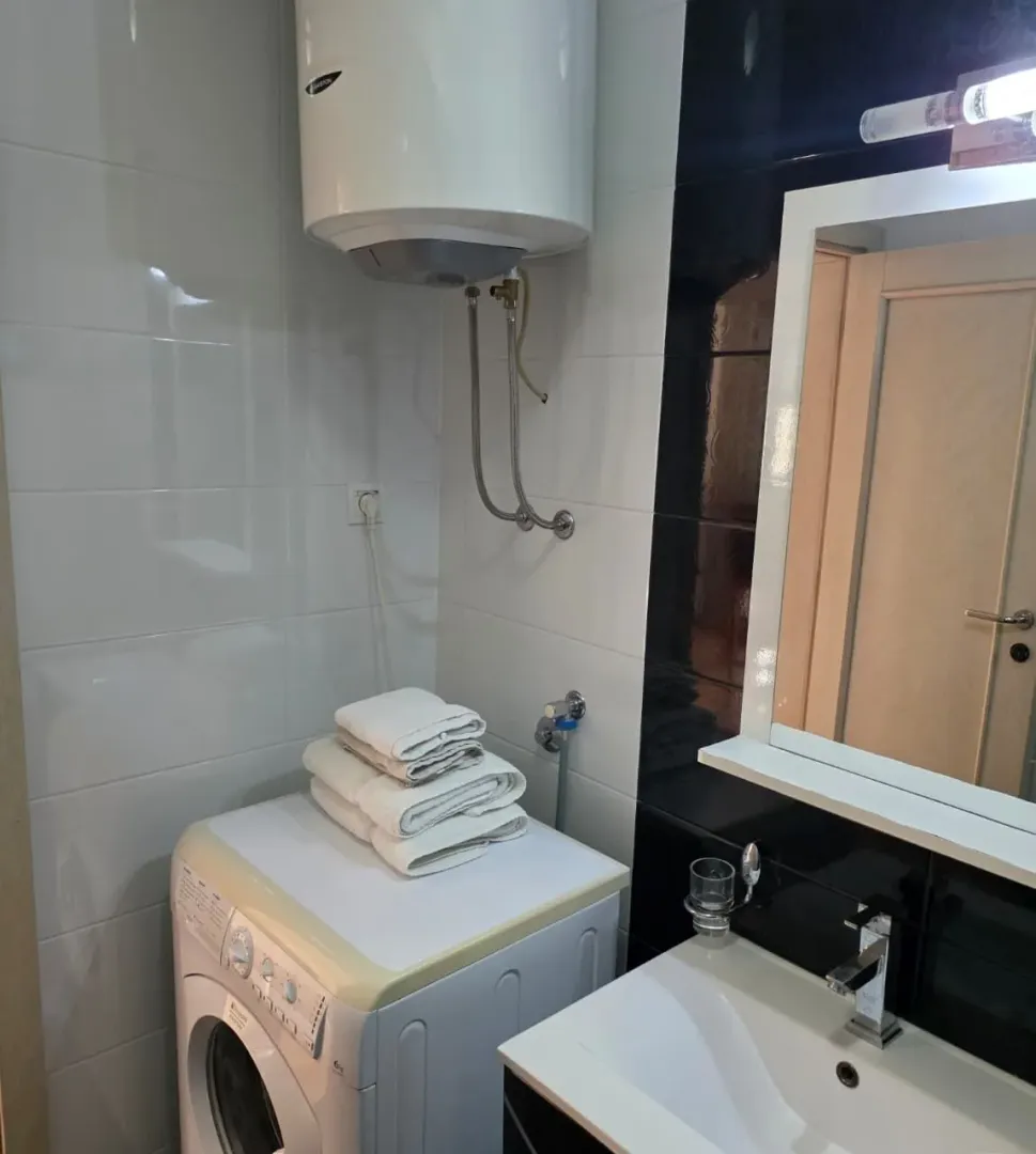 Small bathroom with a sink, washing machine, and water heater.