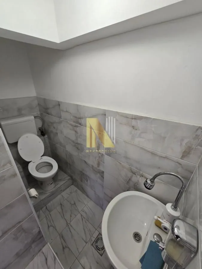 Smaller bathroom with a toilet and a washbasin tiled with ceramic tiles.