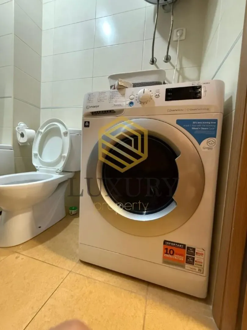 Manje kupatilo sa veš mašinom i toaletom.