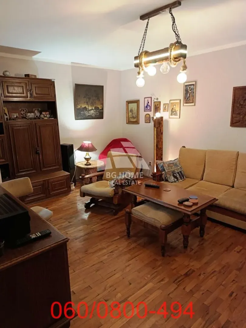 Dnevna soba opremljena drvenim nameštajem i garniturom za sedenje.
