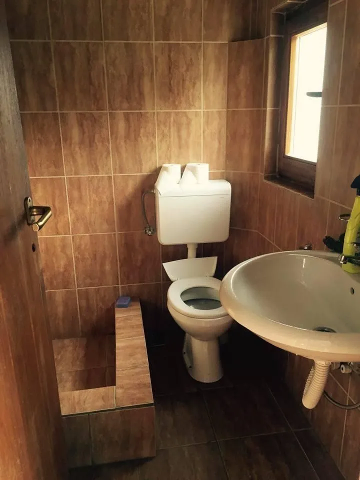 Kupatilo sa braon pločicama, lavaboom i toaletom.