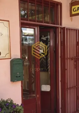 Entrance door of a commercial space with a green mailbox and protective bars. - image 3