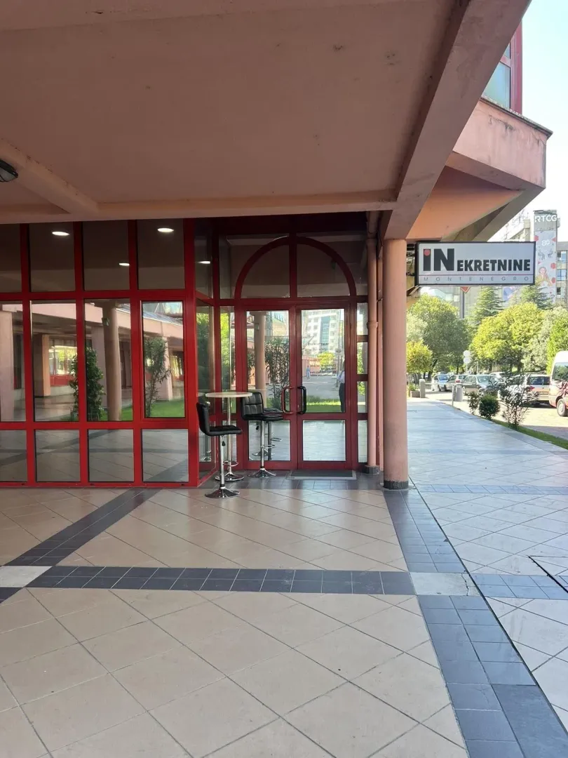 Entrance to a commercial property with red-framed glass doors and windows.