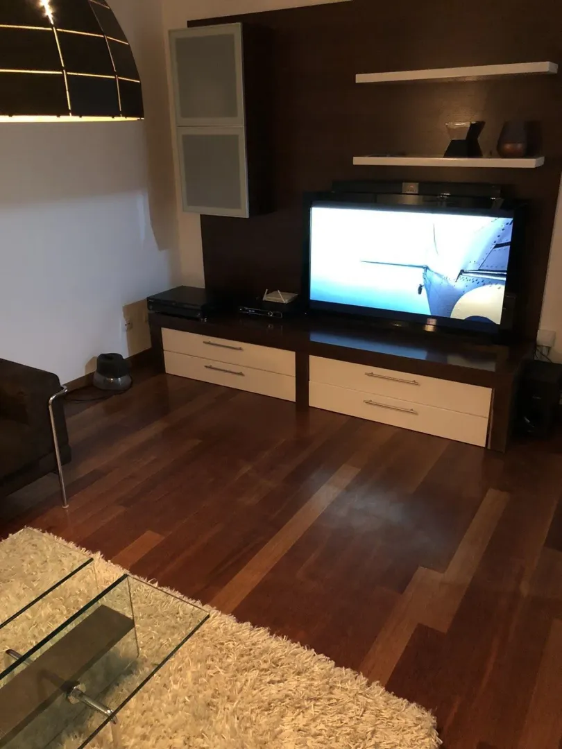 Dnevna soba sa modernom TV komodom i drvenim parketom.