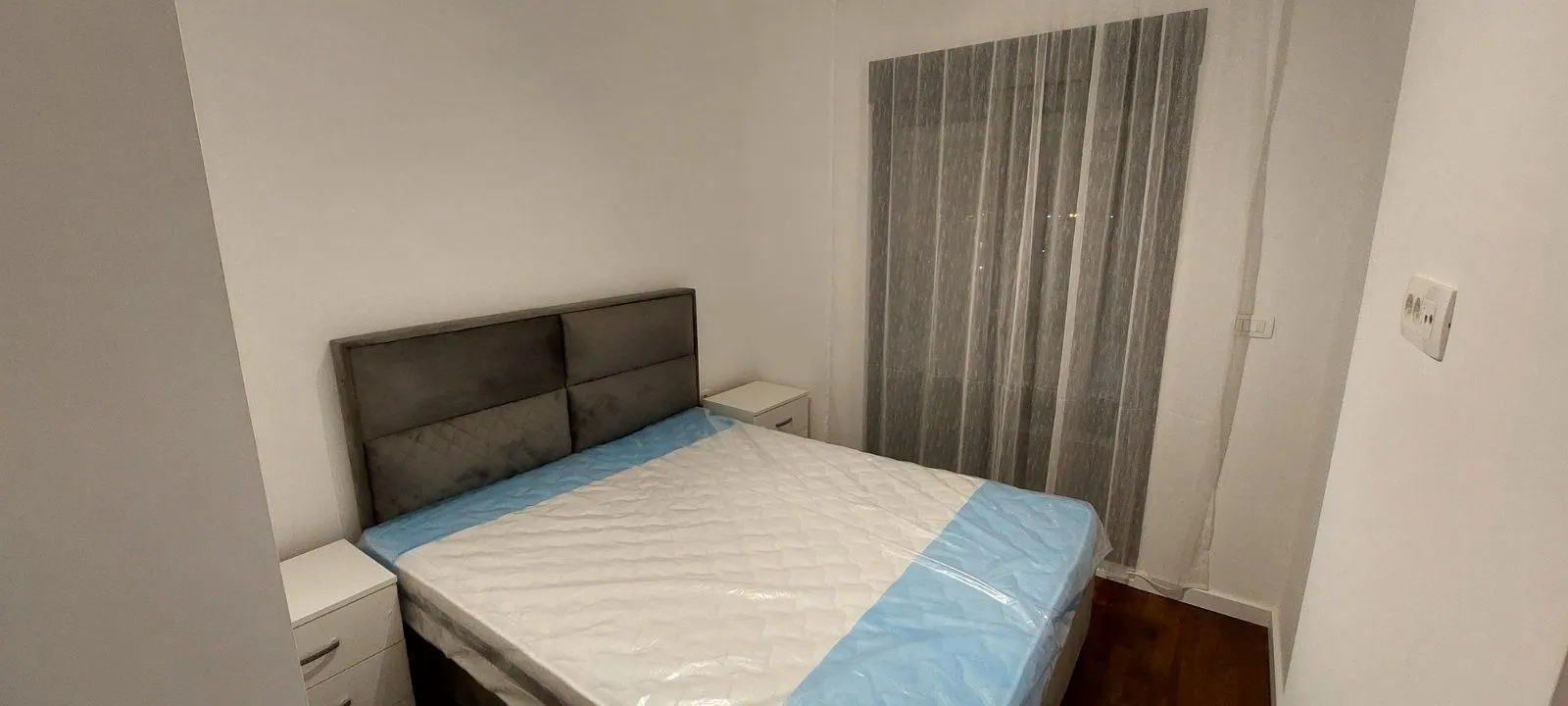 Manja spavaća soba sa bračnim krevetom i noćnim stočićima.