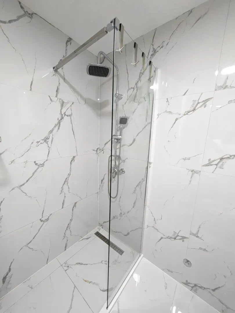 Modernly equipped bathroom with a walk-in shower lined with marble tiles.