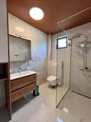 Moderno opremljeno kupatilo sa tuš kabinom, umivaonikom i toaletom.