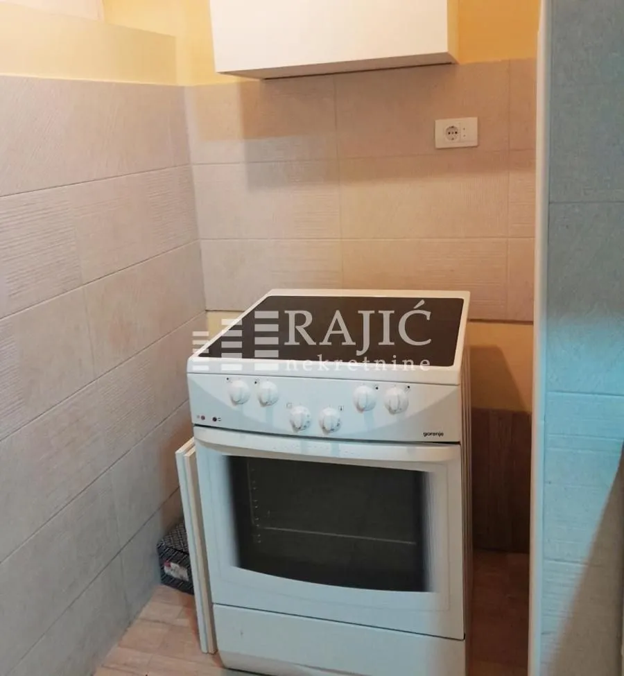 View of part of the kitchen with a stove and ceramic tiles.
