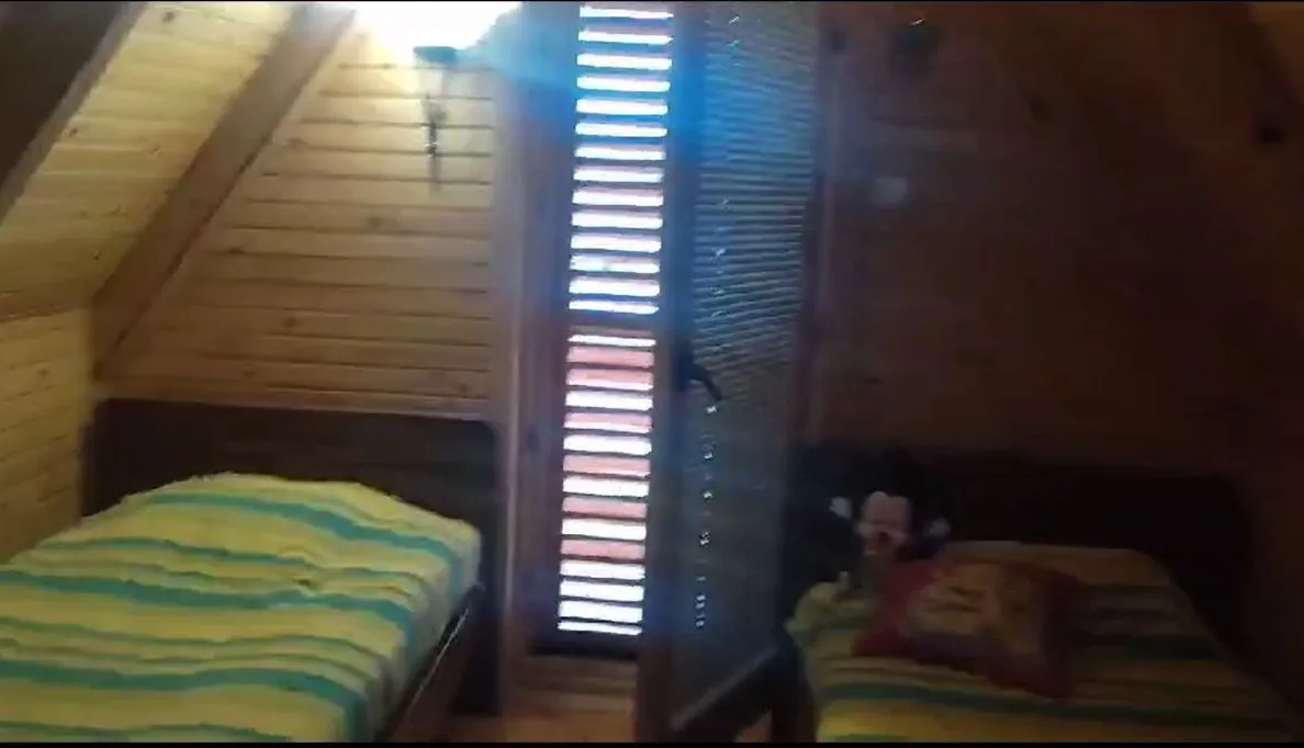 Spavaća soba sa dva kreveta u drvenom ambijentu.
