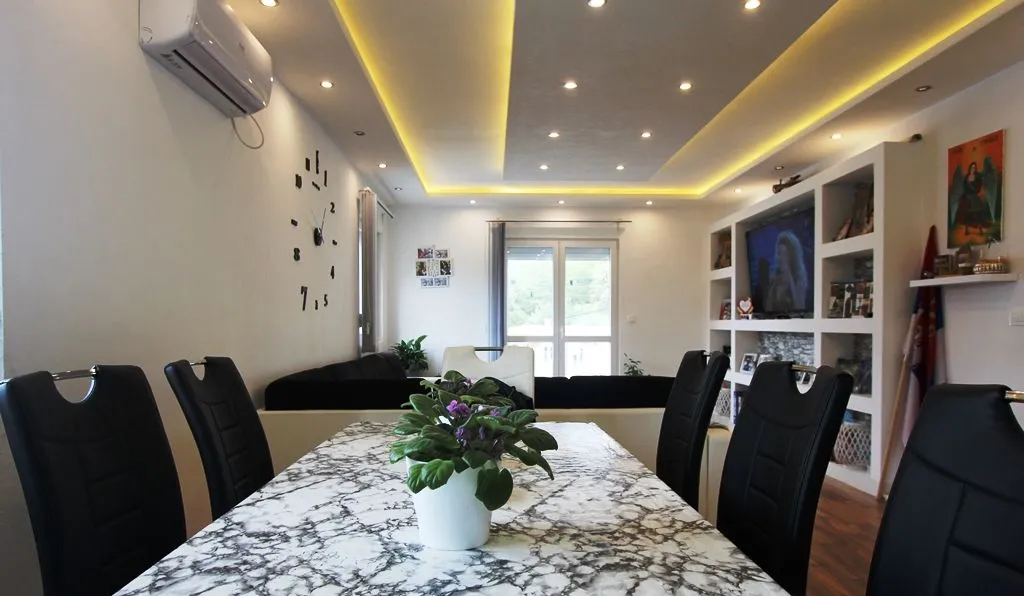 Dnevna soba sa trpezarijom i modernim plafonskim osvjetljenjem.