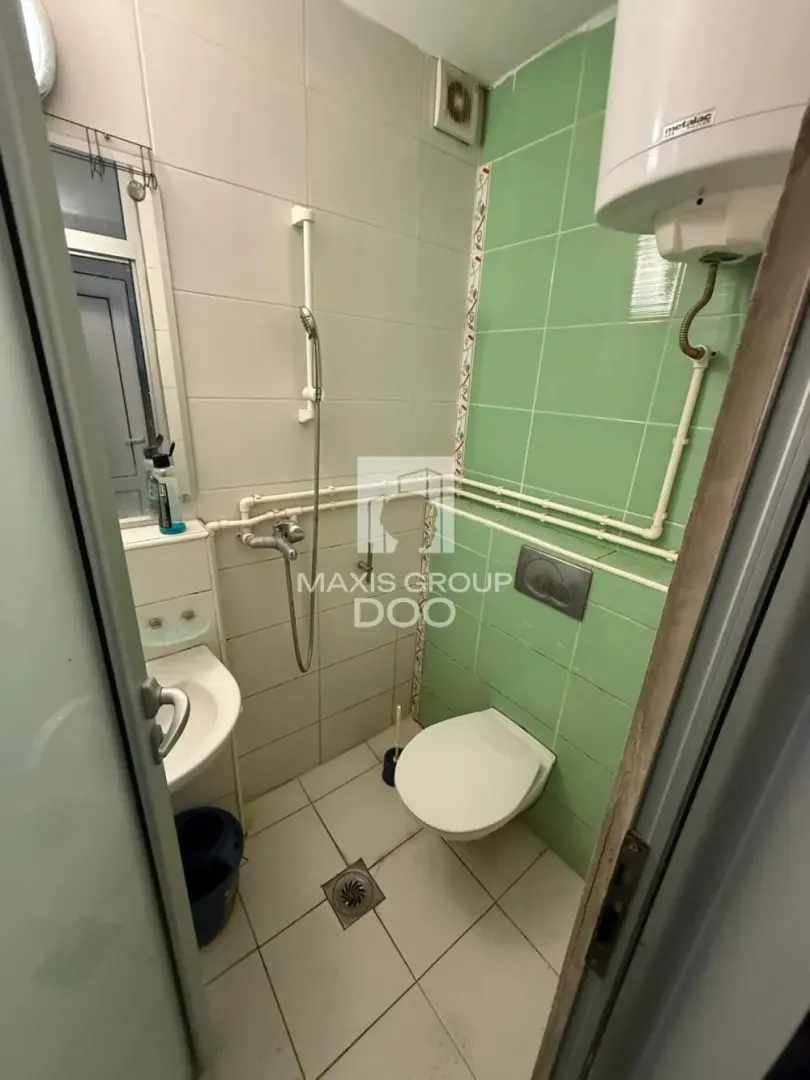 Smaller bathroom with a shower cabin, toilet, and washbasin.