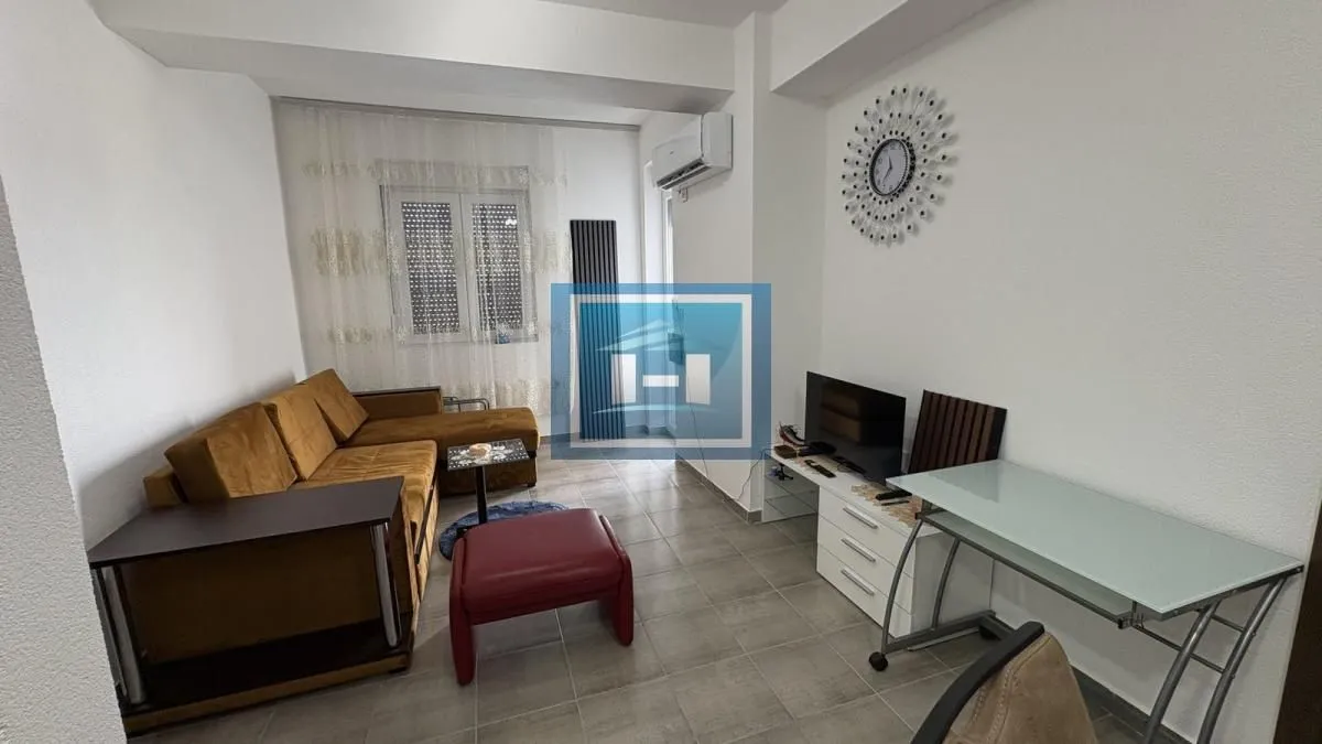 Living room furnished with a sofa, TV, and desk.