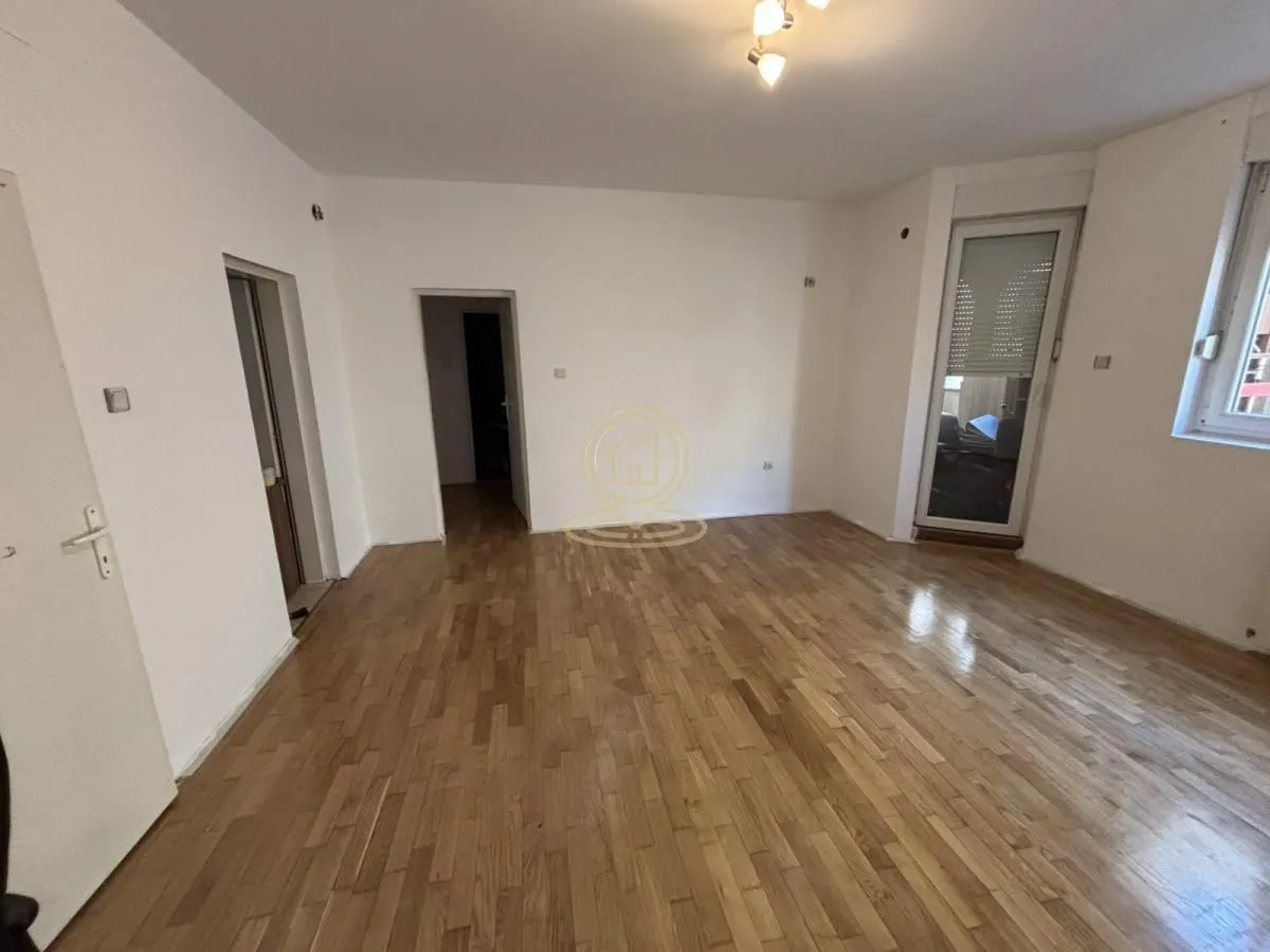 Empty room with wooden parquet flooring, white walls, and access to the terrace.