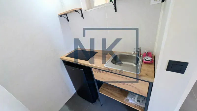 Small kitchen with a sink, built-in cooktop, and refrigerator.