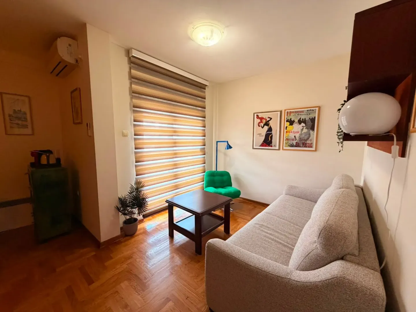 Dnevna soba sa garniturom, stočićem i prozorom sa roletnama.