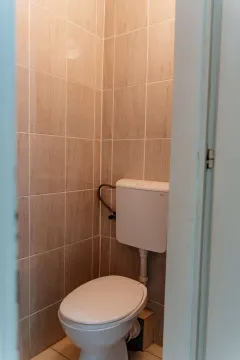 Small toilet room with beige tiles. - image 9