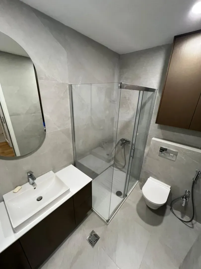 Modern bathroom equipped with a shower cabin, vanity, and wall-hung toilet.