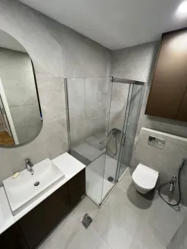 Modern bathroom equipped with a shower cabin, vanity, and wall-hung toilet. - image 19