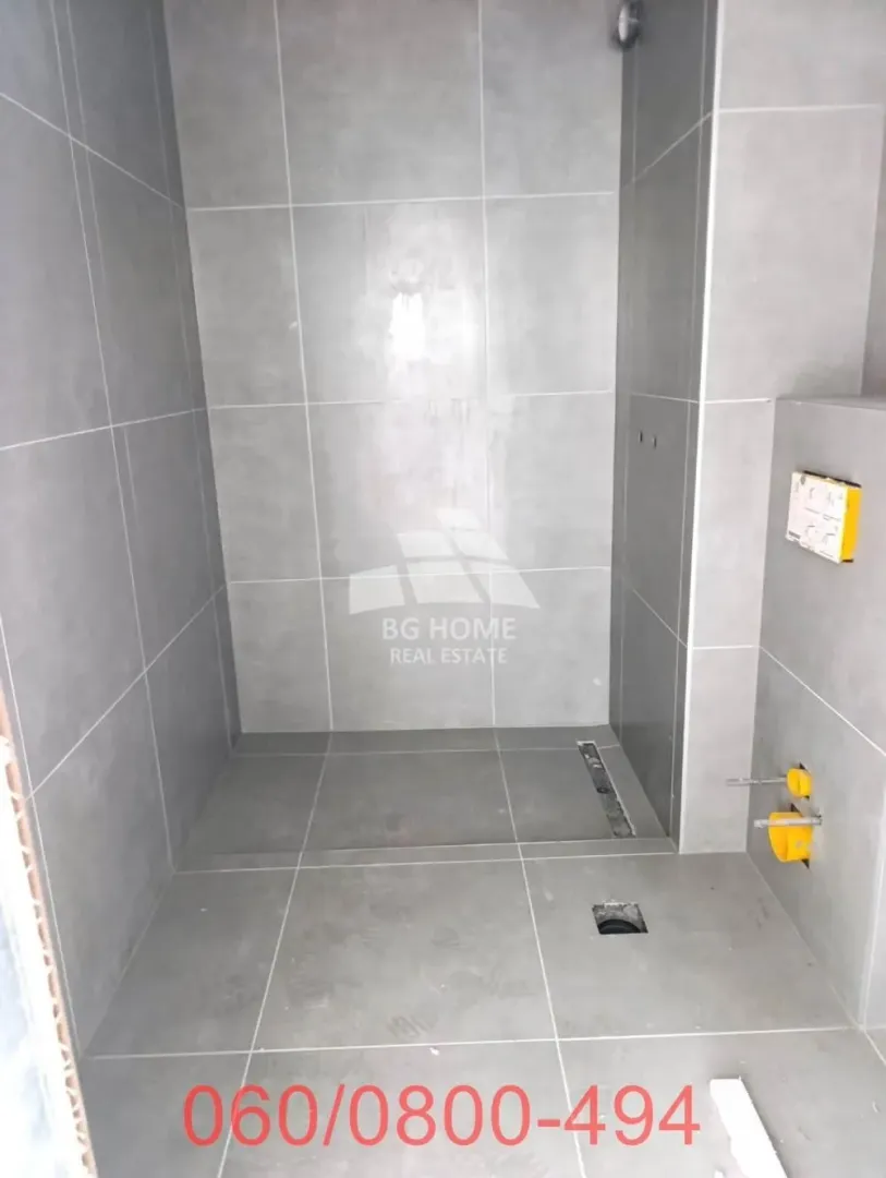 Kupatilo u izgradnji sa sivim pločicama i pripremljenim instalacijama.