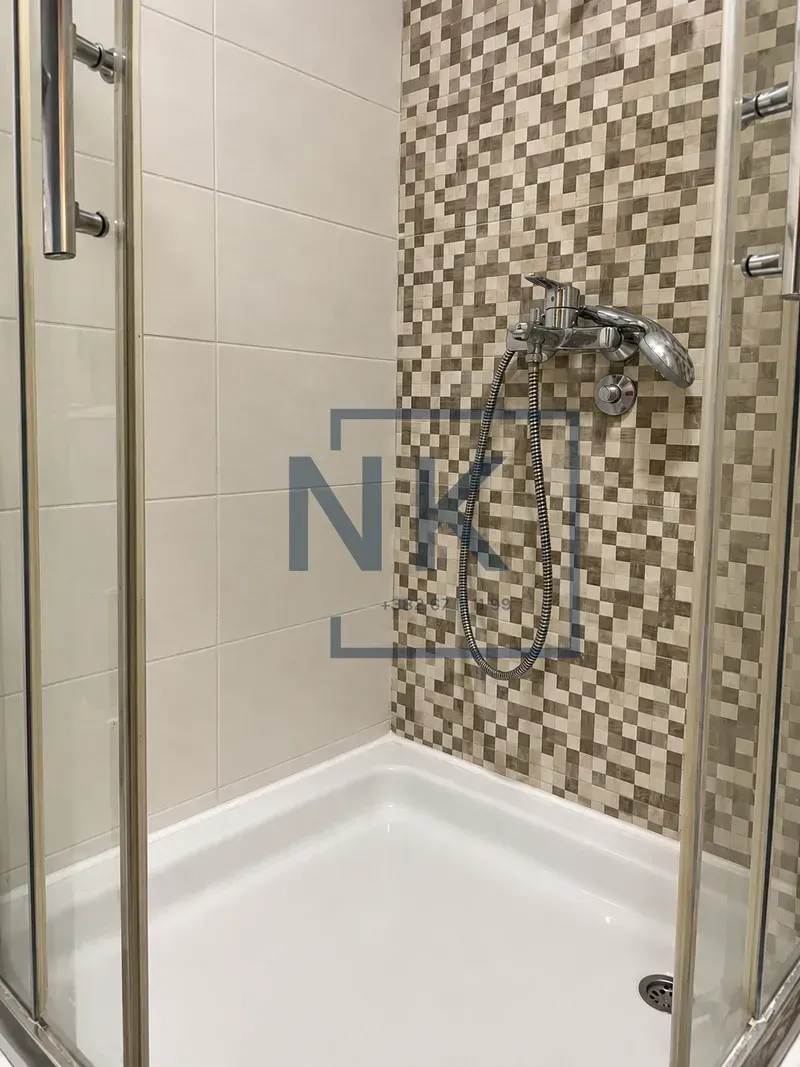 Shower enclosure with ceramic tiles and a faucet.