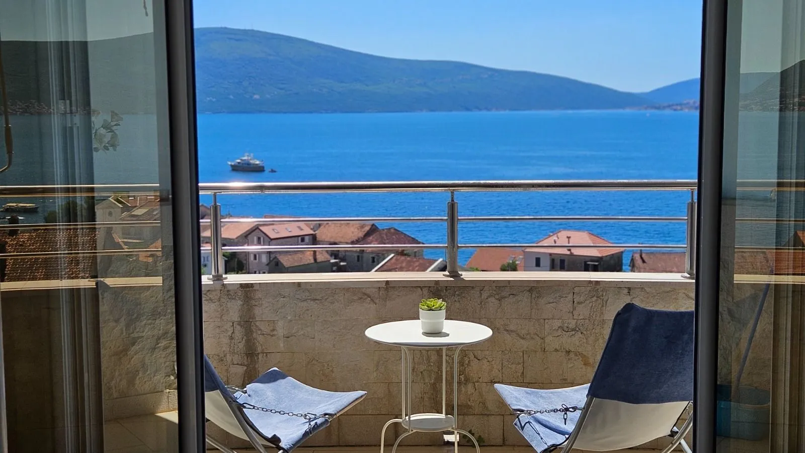 Namješten balkon sa stolom i stolicama i pogledom na more.