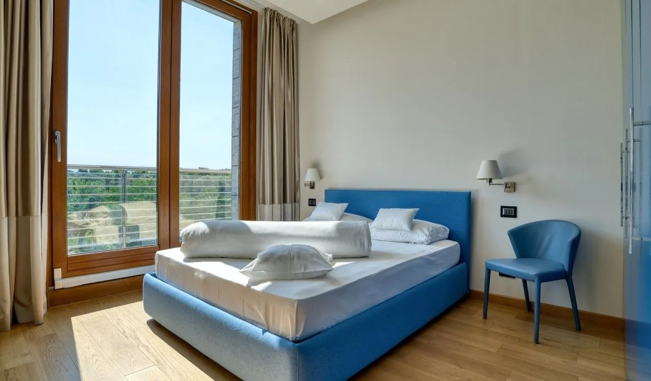 Bedroom with a double bed, a blue armchair, and access to the terrace.