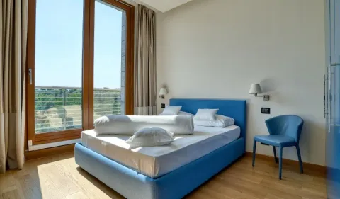 Bedroom with a double bed, a blue armchair, and access to the terrace. - image 8